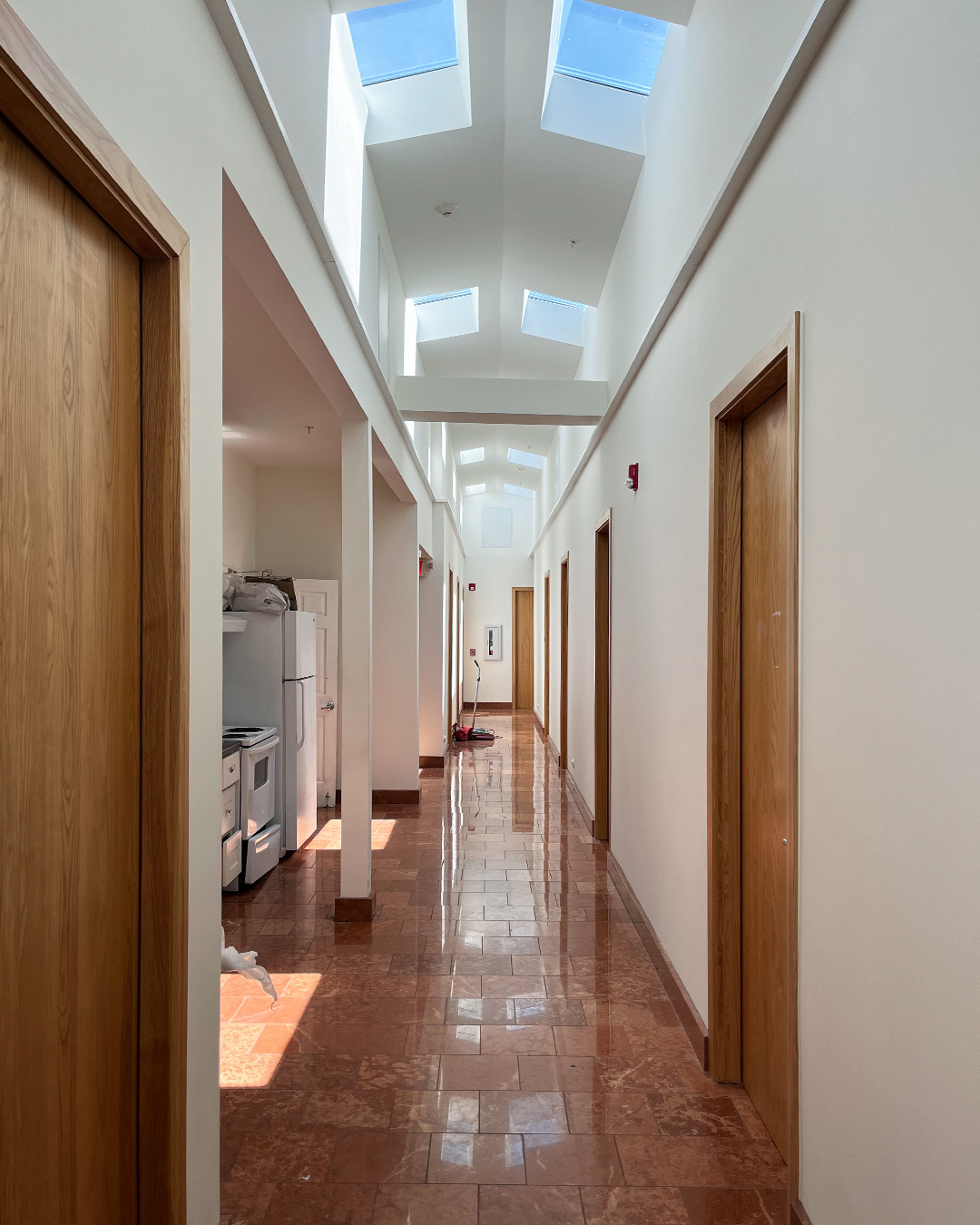 Georgia Windows & Doors custom solid wood interior doors in a spacious, naturally lit institutional hallway with safety features and elegant timber design