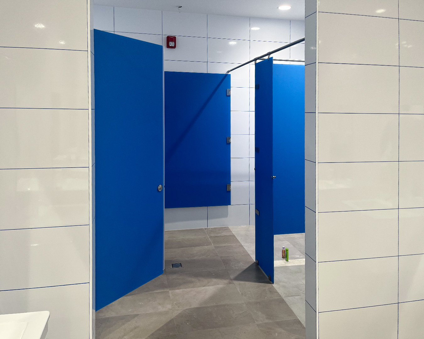 Georgia Windows & Doors custom commercial glass shower enclosures with robust stainless steel hardware and safety-rated blue panels, designed for high-traffic institutional and educational facilities